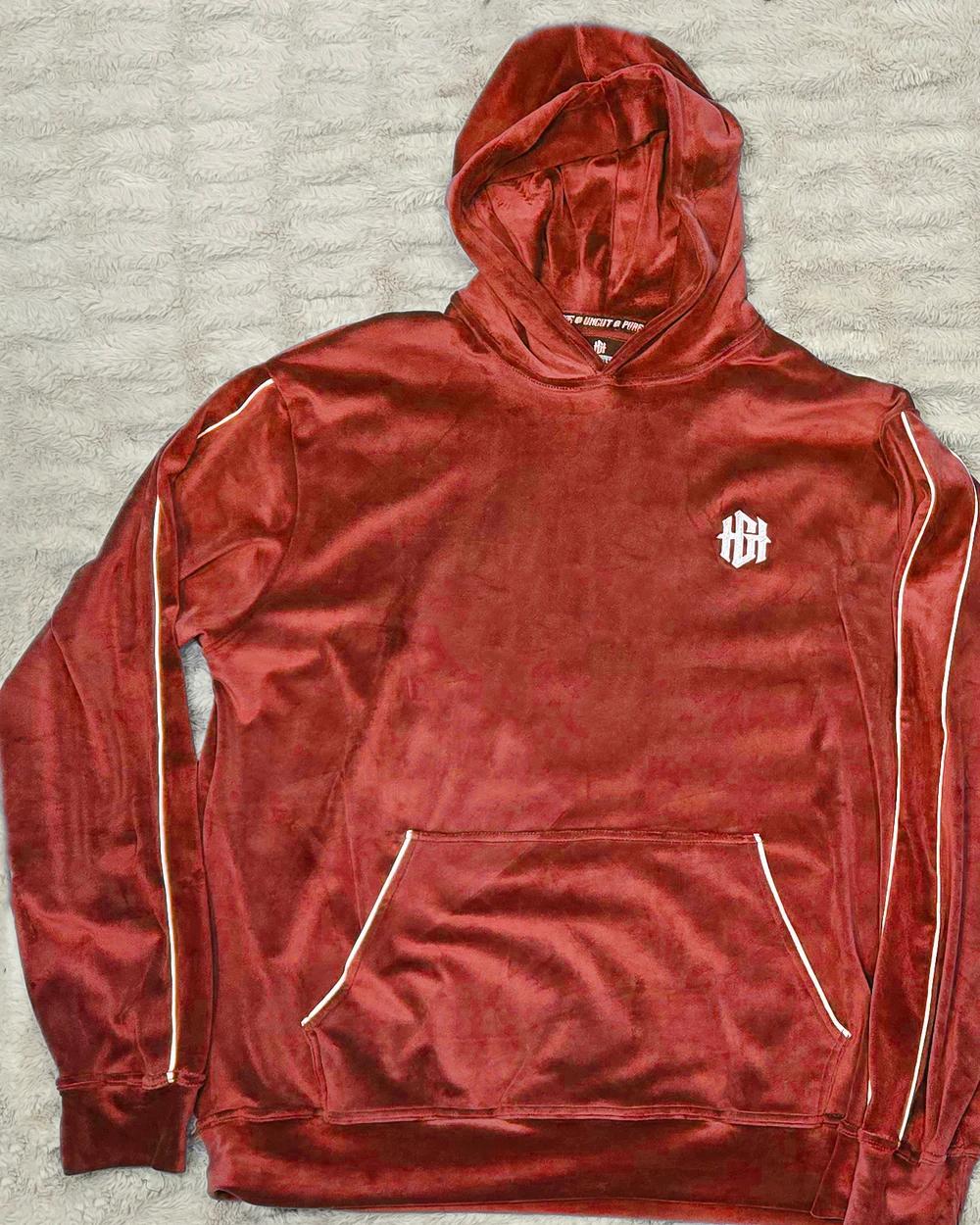 Red velour hoodie laid flat, with white piping and a white HGH monogram on the chest